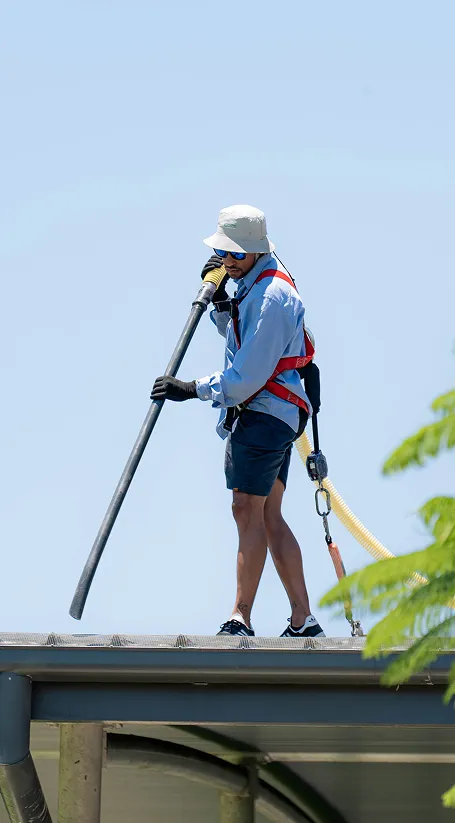 Global Vac technician operating high-powered vacuum equipment on a roof